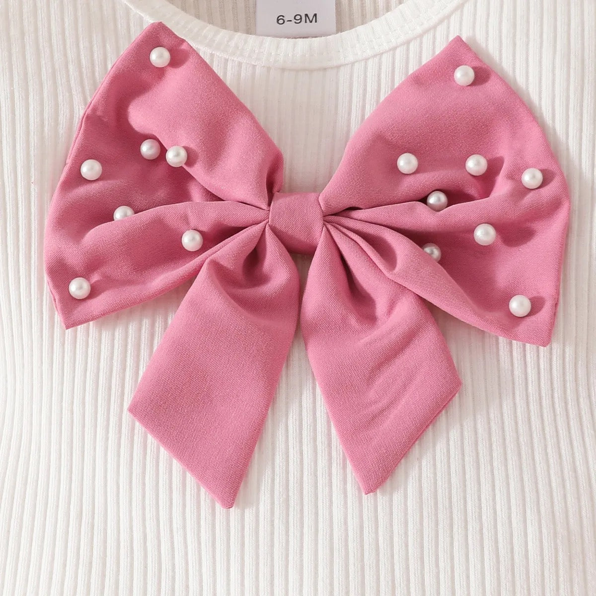 Set de lazo con perlas en pantalón corto y gorro.